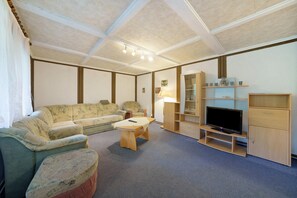 A living room with a sofa, a coffee table, a TV, and built-in shelving.