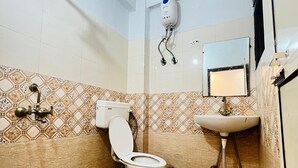 A bathroom with a toilet, sink, and a decorative bucket. - Roomshala Hotel Pub G (New Delhi)