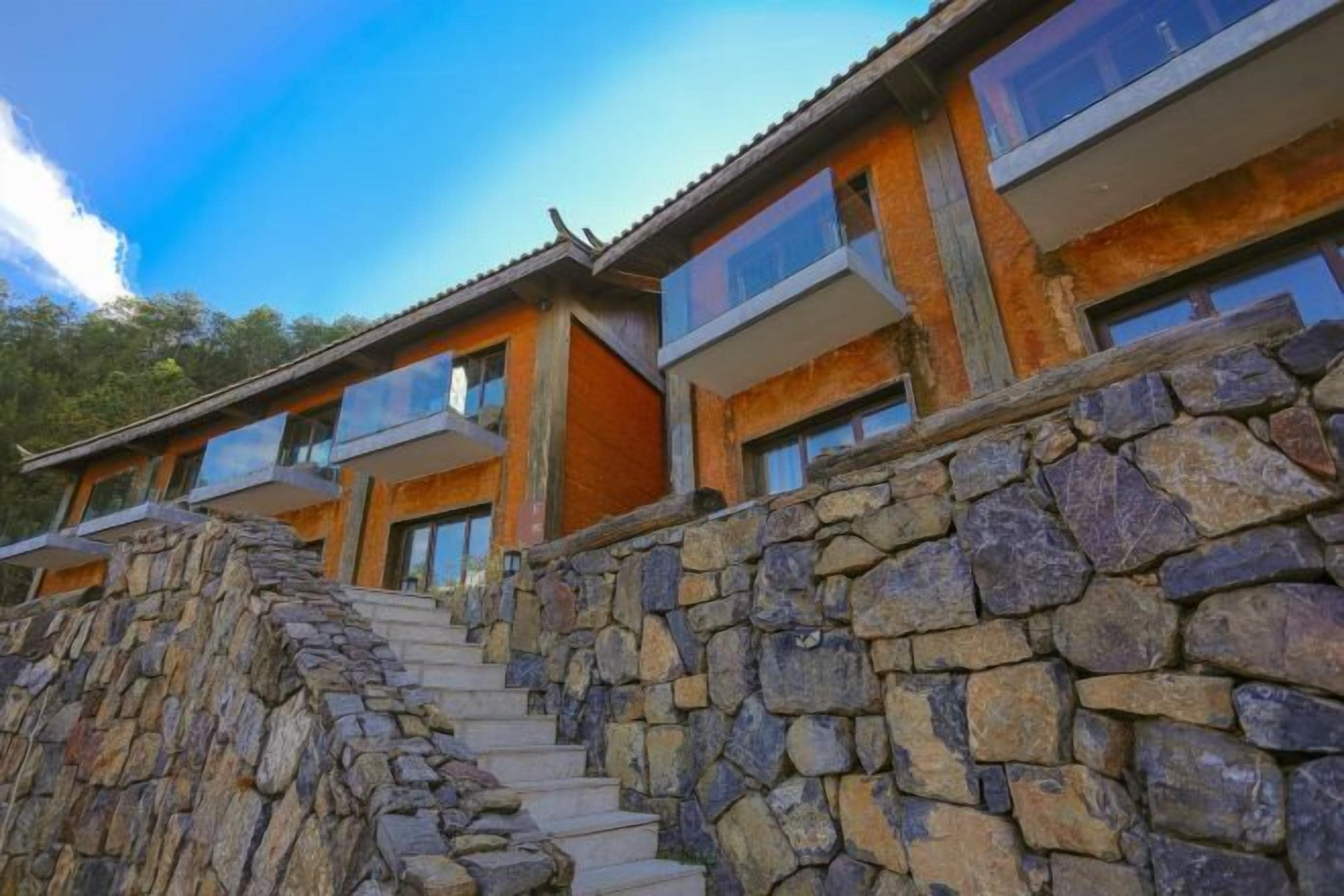 A modern building with a stone facade, large windows, and a stone staircase leading to the entrance.