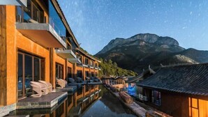 A hotel with a reflection pool, traditional architecture, and a mountain backdrop. - Wuhu Muyun Mountain Villa (Ninglang)