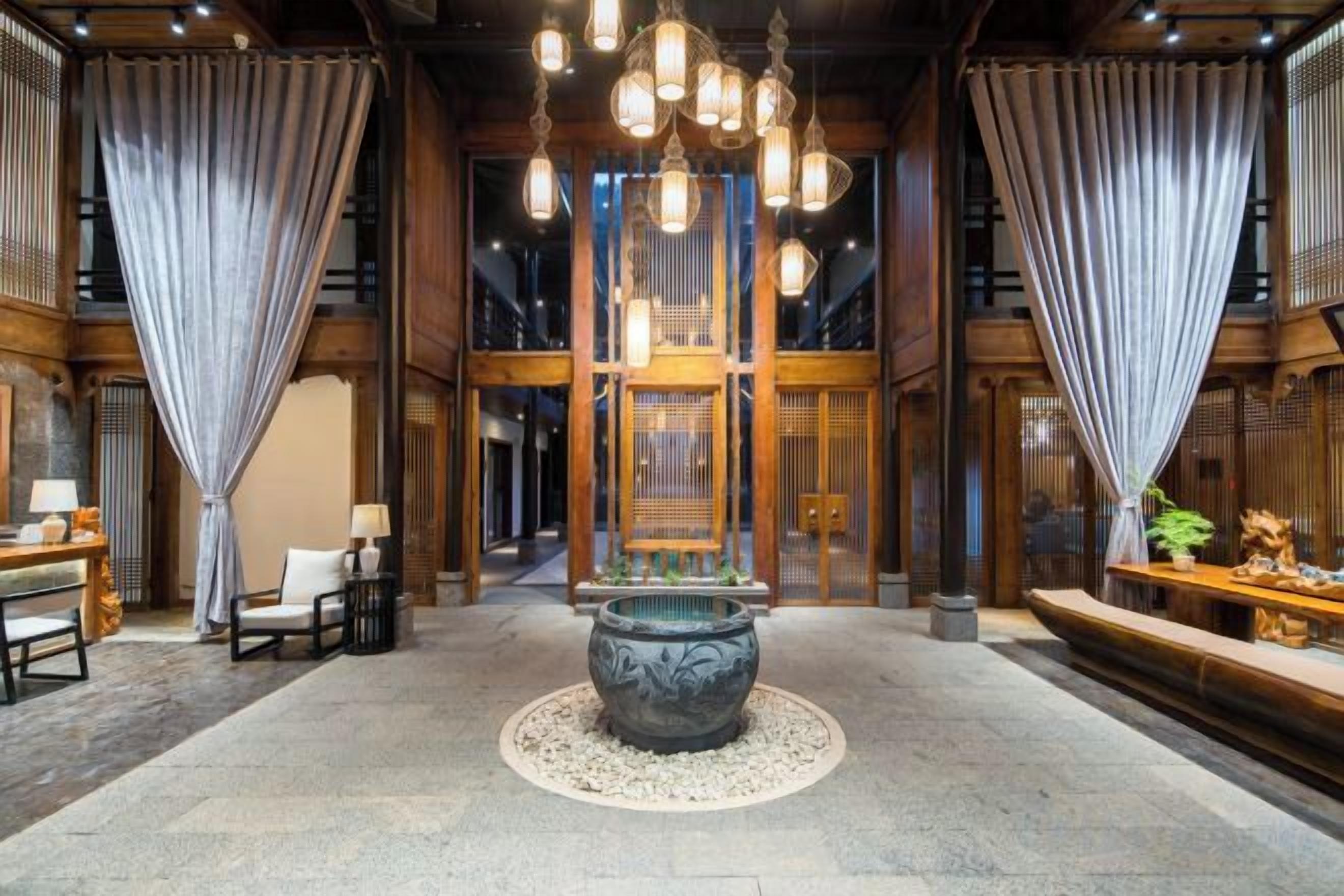 A spacious lobby with a large central fountain, wooden paneling, and a seating area with tables and chairs.