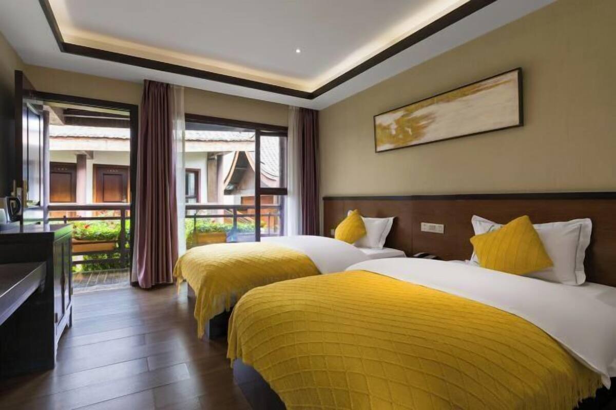 Een hotelkamer met twee bedden, een bureau en een groot raam.