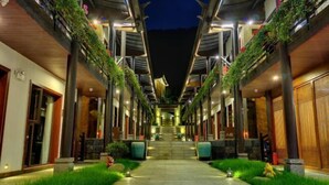 A hotel corridor with a central staircase, flanked by rooms with balconies adorned with plants. - Wuhu Muyun Mountain Villa (Ninglang)