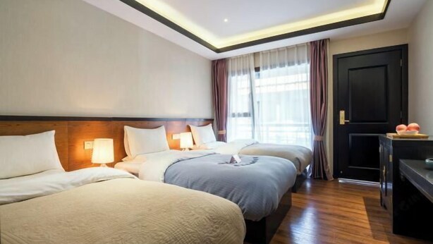 A hotel room with three beds, a desk, and a door. - Wuhu Muyun Mountain Villa (Ninglang)