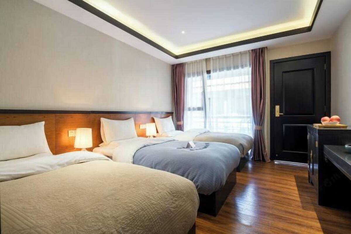 Een hotelkamer met drie bedden, een bureau en een deur.