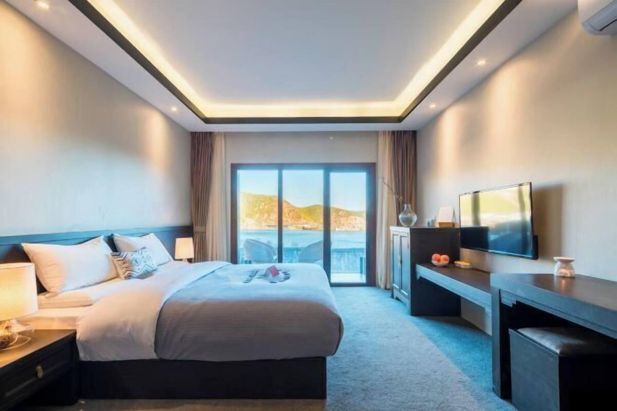Een moderne hotelkamer met een groot bed, een bureau, een flatscreen televisie en uitzicht op het omliggende landschap.