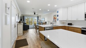 A kitchen with white cabinets, a large island, and a ceiling fan. - Relaxing 1 Bedroom Condo in Harbor Point – SanDestin Golf and Beach Resort (Miramar Beach)