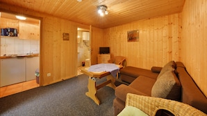 Un intérieur en bois comprenant un coin cuisine, un canapé et un téléviseur.