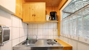 Una cocina con armarios de madera, un lavamanos de acero inoxidable, una cafetera y una ventana con vistas.