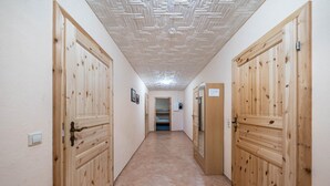 Ein Korridor mit Holztüren, einer Decke mit geometrischem Muster und einem gefliesten Boden.