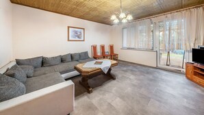 Ein Wohnzimmer mit einer Couch, einem Holztisch, einer TV-Konsole und einer Holzbalkendecke.