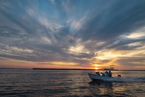 Een boot op kalm water tijdens de zonsondergang, met een heldere lucht.
