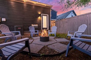 A backyard with a fire pit, outdoor seating, and a wooden fence. - Indy Gem | 3BR w/ Fire Pit, Games + Prime Location (Indianapolis)