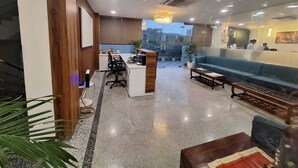 A modern reception area with a reception desk, seating area, and a view of the cityscape. - Hotel RR Galaxy (Gurugram)