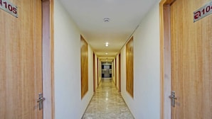 A hallway with wooden doors on either side, numbered 105 and 106, leading to a room with a marble floor. - Hotel RR Galaxy (Gurugram)