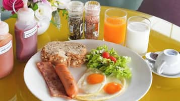 A breakfast plate with eggs, sausage, toast, and salad on a yellow table.