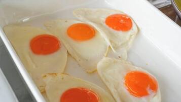 A white rectangular dish containing four fried eggs with runny yolks.