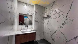 Une salle de bain avec un mur en marbre, un meuble-lavabo en bois, un miroir et un porte-serviettes.