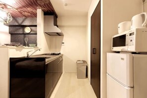 A compact kitchen with a sink, stove, microwave, and refrigerator. - Ra Premier K (Osaka)