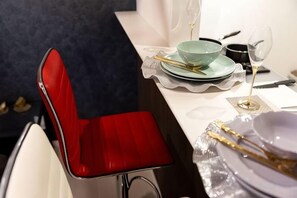 Una mesa de comedor dispuesta con platos, cubiertos y una copa.