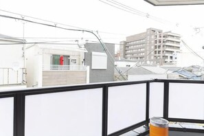 En balkon med udsigt til en bygning med flere etager og en rød genstand på jorden.