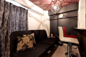 Una habitación con sofá, una silla, una mesita y un reloj de pared.