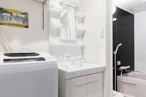 A modern bathroom with a white sink, mirror, and shower. - Ra Premier K (Osaka)