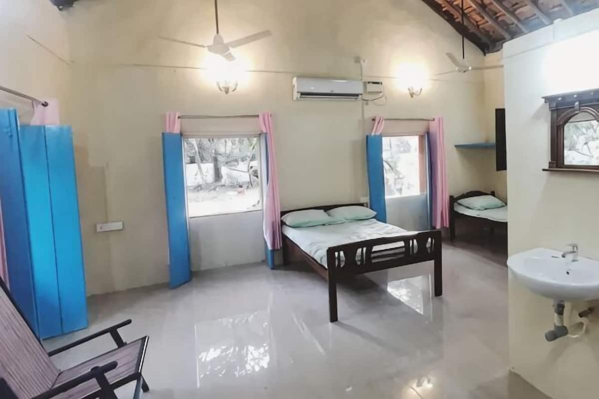 A bedroom with a bed, a chair, a sink, and a window.