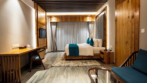 Une chambre à coucher moderne avec un plafond en bois, un lit recouvert d’une couverture bleue, un bureau et une chaise.