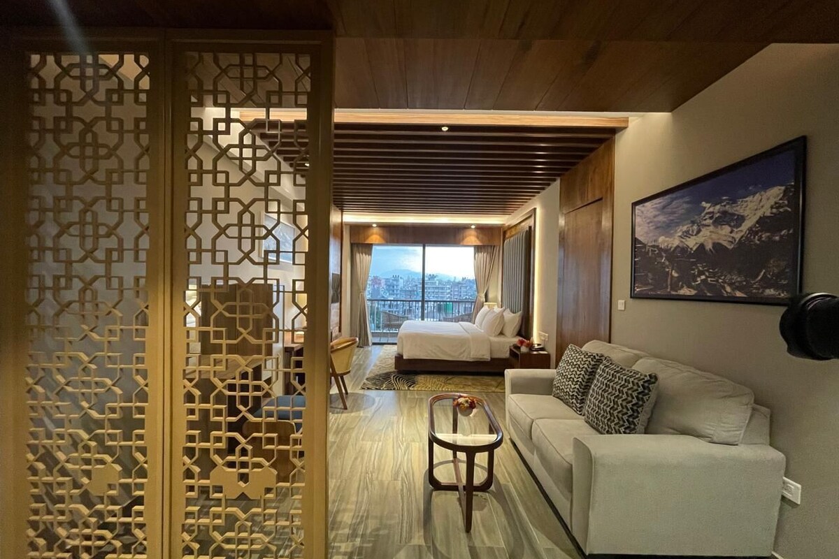 Une chambre d’hôtel comprenant un lit, un canapé, une table basse et un paravent décoratif.