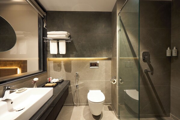 A modern bathroom with a glass shower enclosure, a white toilet, and a vanity with a mirror. - Soaltee Westend Lakeside Pokhara (Pokhara)