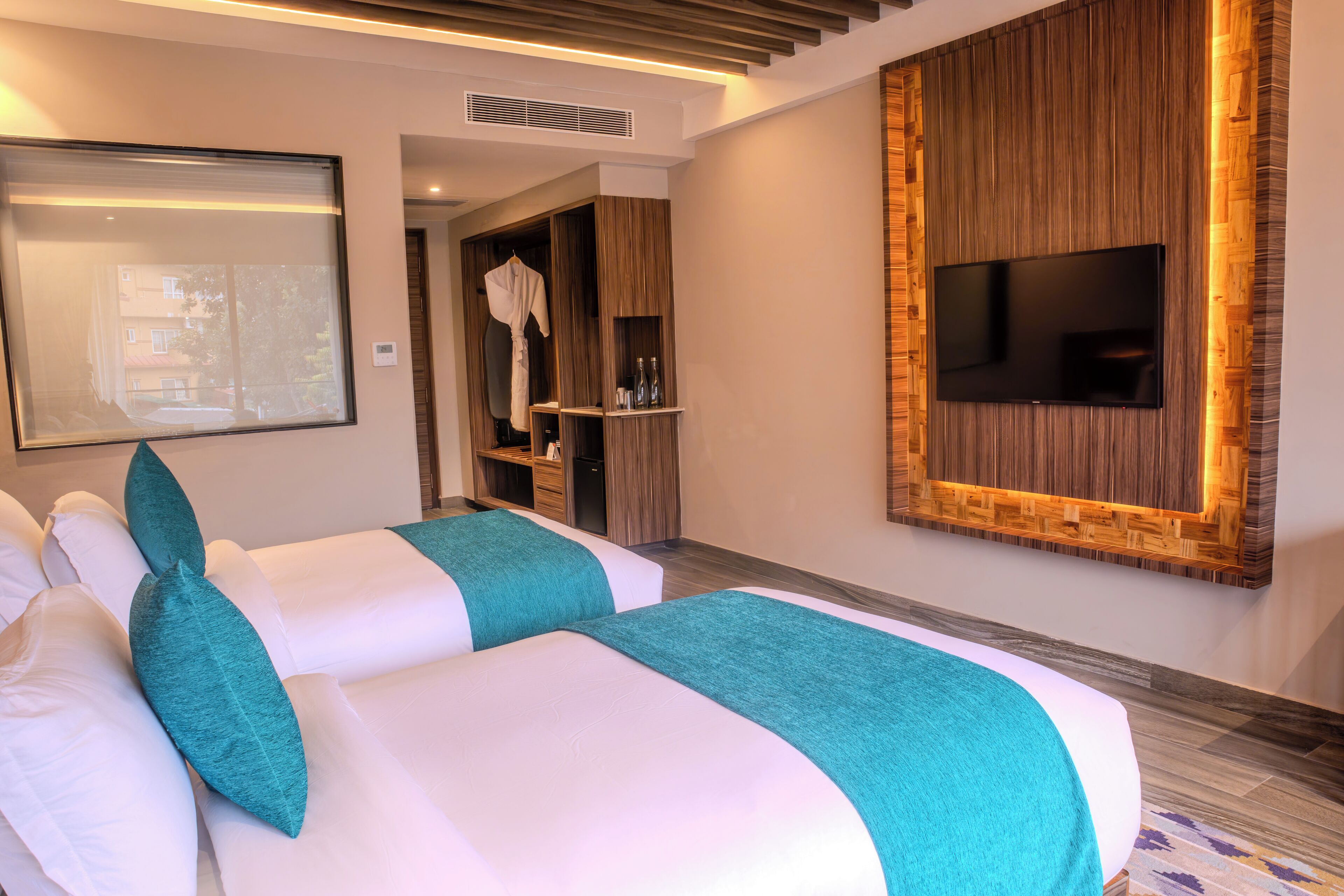 A hotel room with two beds, a TV mounted on the wall, and a mirror.