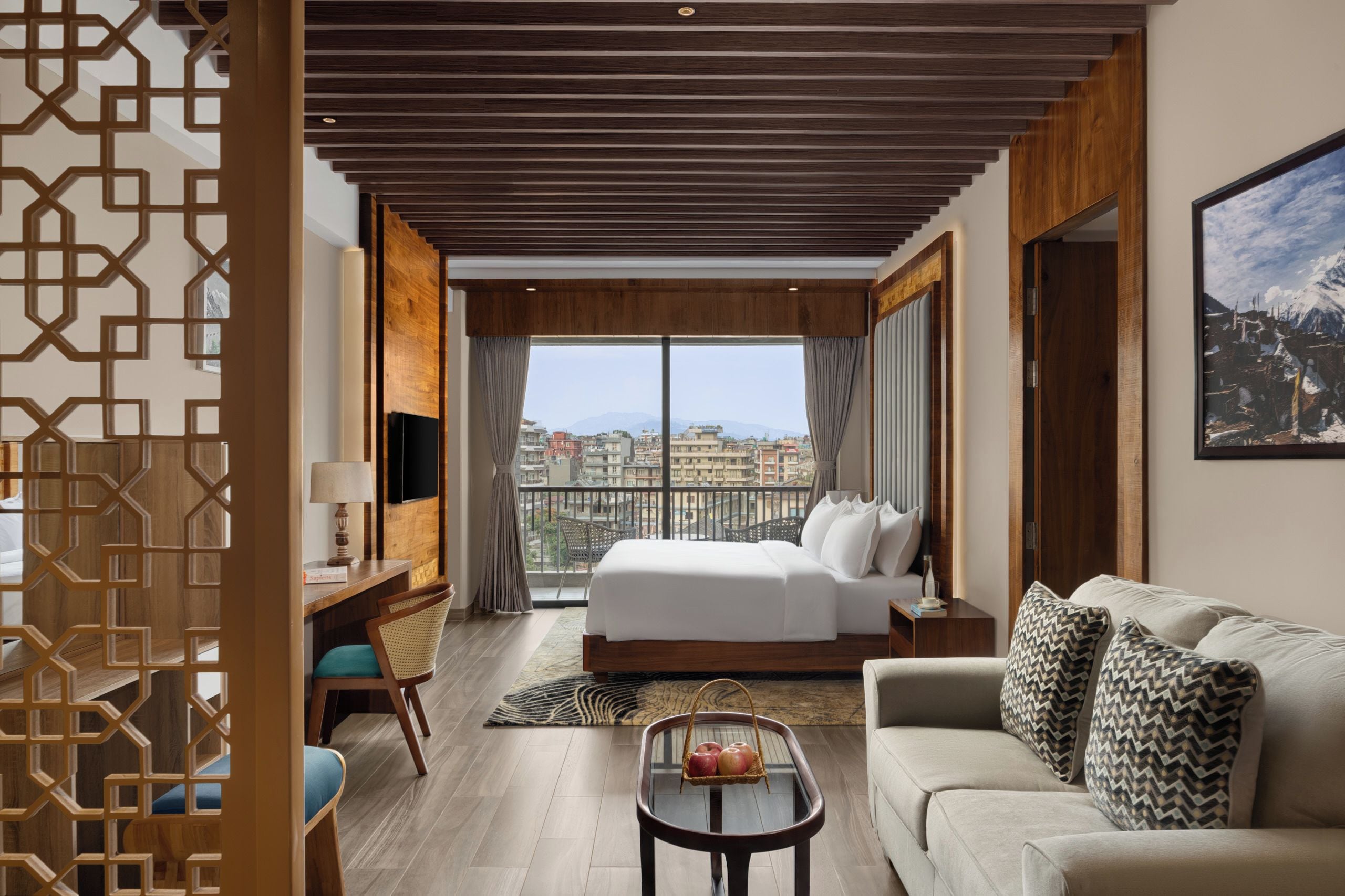 A hotel room with a bed, a sofa, a desk, and a view of the city.