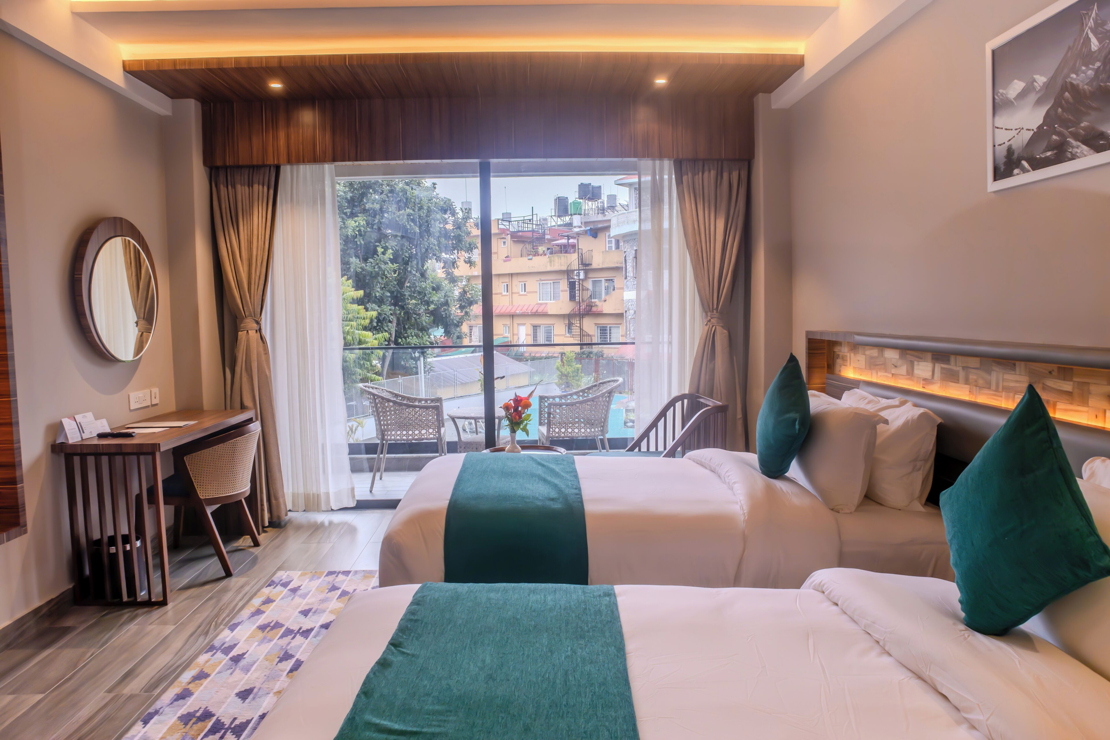 A hotel room with two beds, a desk, a chair, and a view of the cityscape.