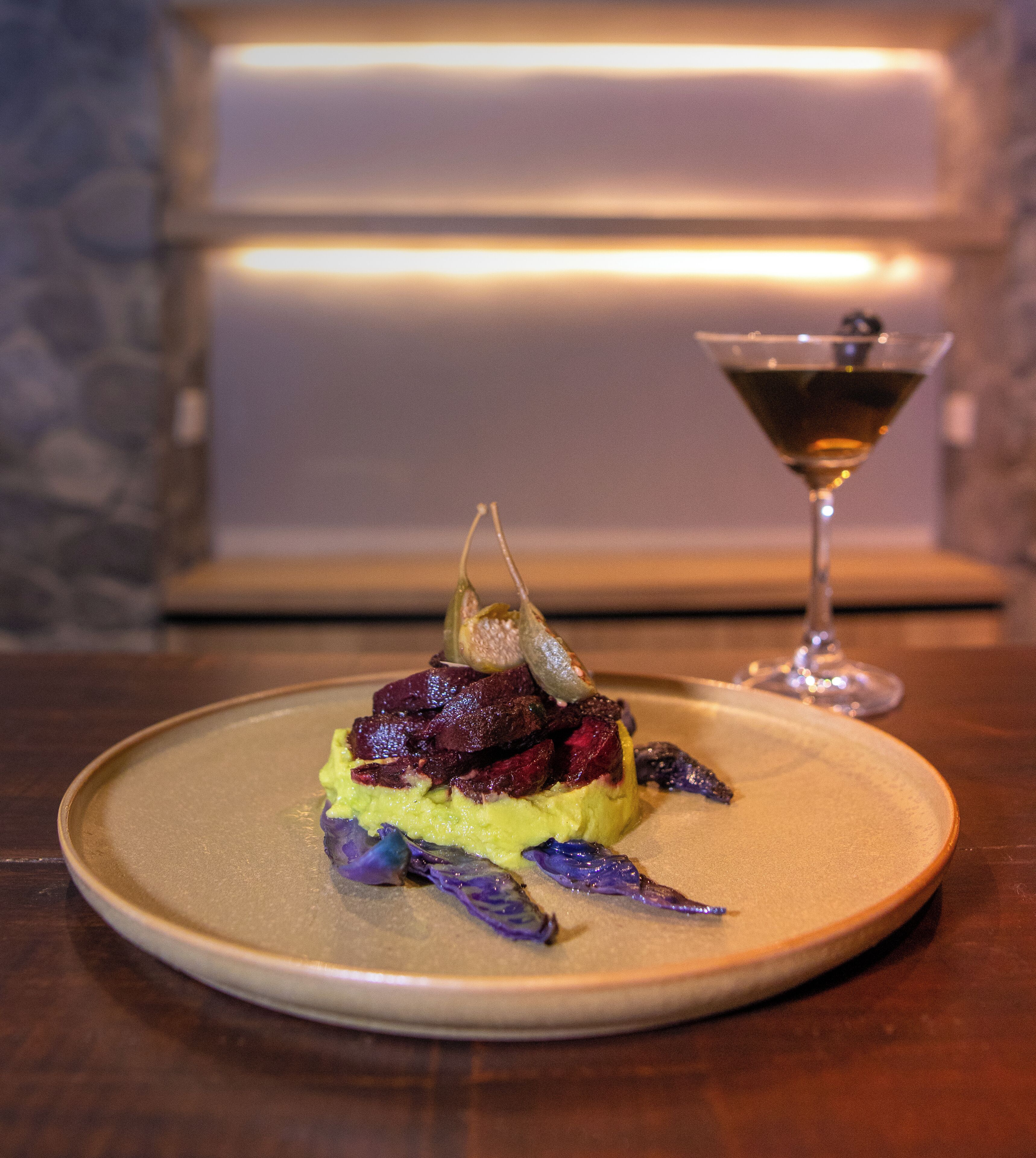 A plate of food with a glass of red wine on a table.