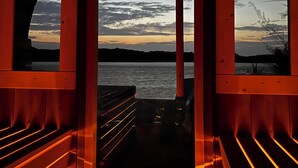 A wooden deck with a view of a sunset over water.