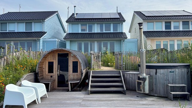 A residential area with three houses, a wooden sauna, and a pool.