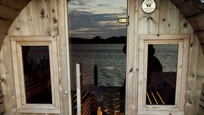 A wooden boat cabin with a view of the water, a door, and two windows.