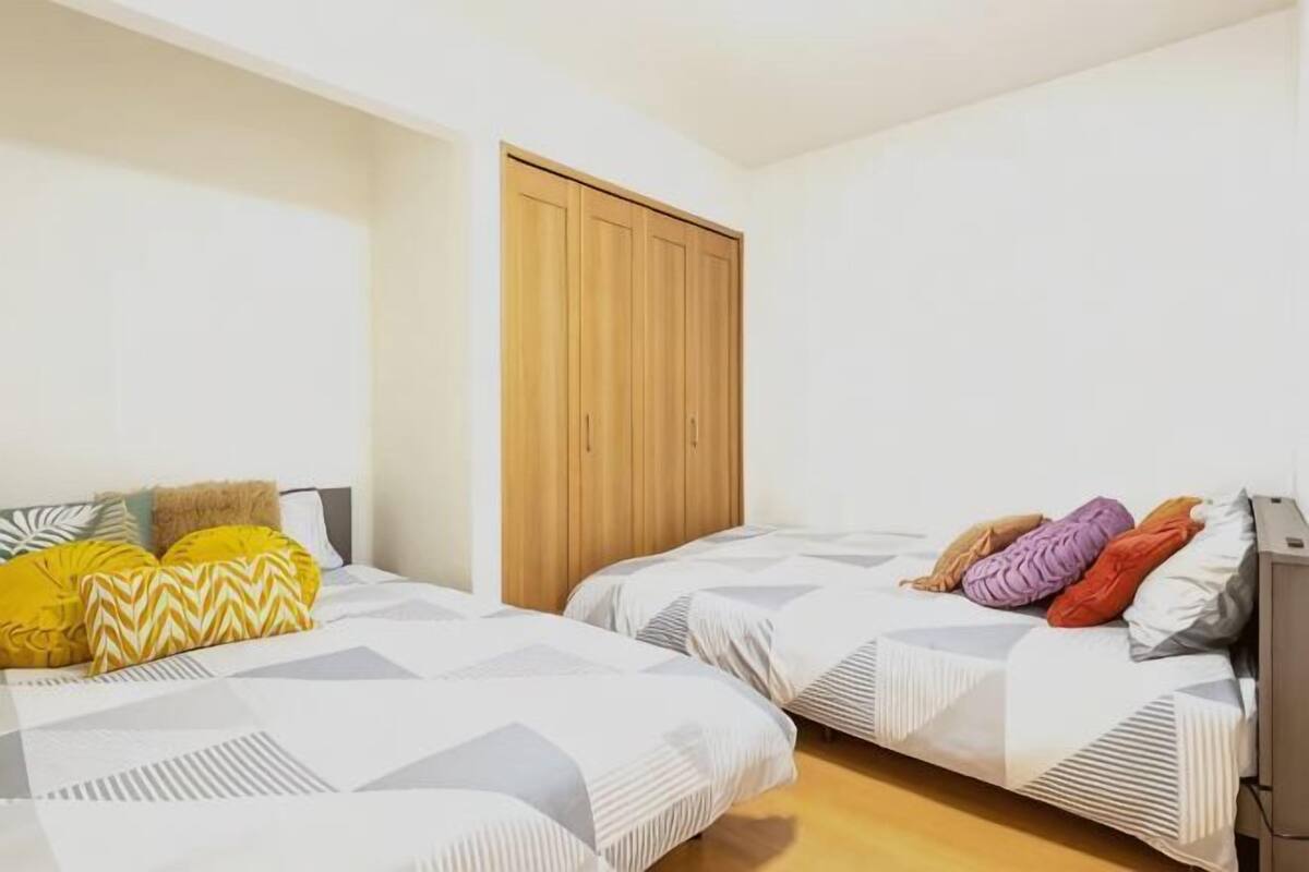 Une chambre avec deux lits, une armoire et un bureau.