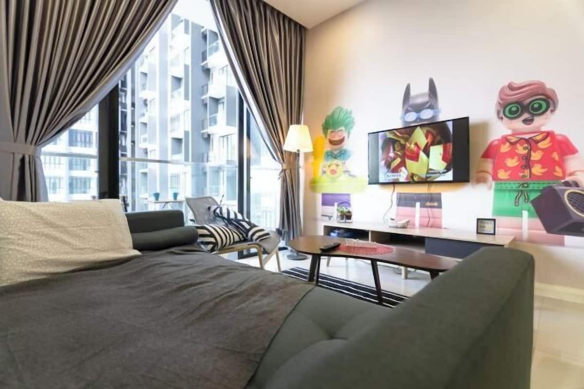 A hotel room with a bed, a sofa, a TV, and a window with curtains.