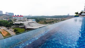 A long swimming pool with a view of buildings and a hilly landscape.