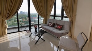 A modern living room with a sofa, a chair, a small table, and a view through large windows. - Cozy & Luxury Apartments, 5mins to Legoland (Iskandar Puteri)