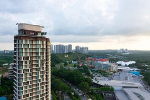 A high-rise building with multiple floors, surrounded by greenery and other buildings. - Cozy & Luxury Apartments, 5mins to Legoland (Iskandar Puteri)