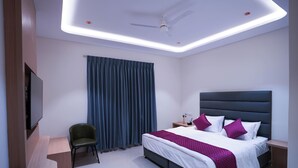 Quarto de hotel moderno com uma cama, uma escrivaninha, uma cadeira e uma televisão.