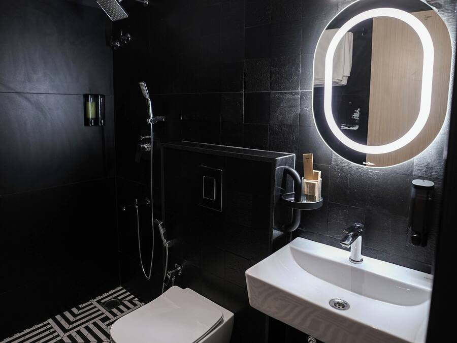 Een moderne badkamer met een zwart-wit betegelde vloer, een wit toilet, een wastafel met spiegel en een douche.