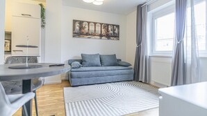 A modern living room with a grey sofa, a round table, and a patterned rug. - Cozy 1BR+1LR w/ Balcony, 9-Min to City Center (Vienna)