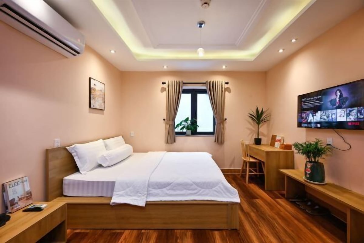 Une chambre d’hôtel avec un lit, un bureau, une télévision et une fenêtre avec des rideaux.