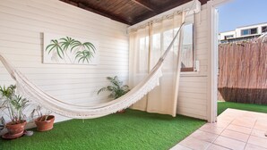 Uma rede, plantas em vasos, piso de grama sintética verde e teto de madeira.