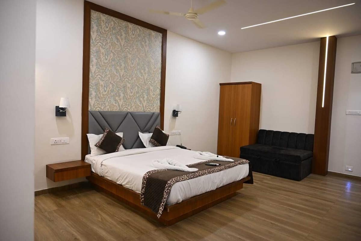 Ein modernes Hotelzimmer mit einem großen Bett, einem Kleiderschrank, einer Sitzecke und einem Deckenventilator.