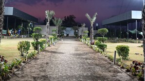 A paved pathway leading to a building with a modern design, surrounded by small trees and plants. - Nicolas Farm & Resort (Parsivni)